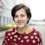 Photo of Lela Rekhviashvili, a smiling woman with dark hair, wearing a red pullover