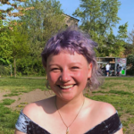 Photo of Lina Kieseritzky, a purple hair young woman sitting in a fresh green area